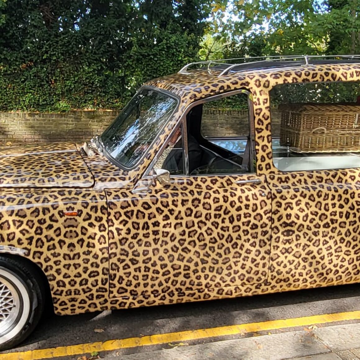 Leopard print hearse for bespoke farewell Hand woven english wicker coffin with red rose heart of flowers