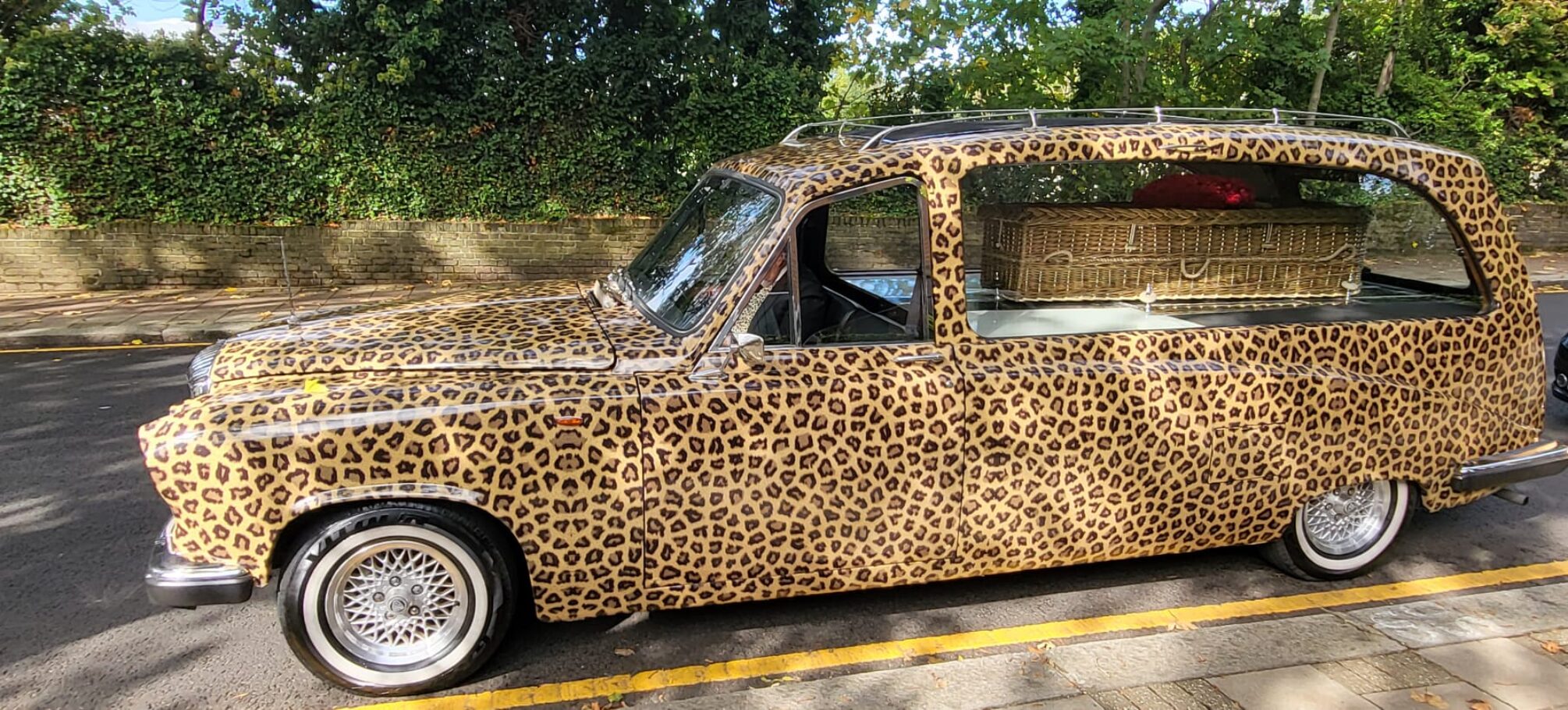 Leopard print hearse for bespoke farewell Hand woven english wicker coffin with red rose heart of flowers