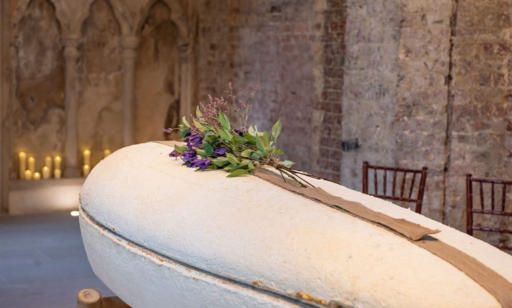 Mushroom Coffin laid out in a chapel with candles and floral details