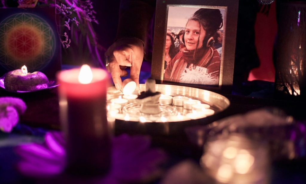 Memorial shrine with candles, photographs and offerings in a softly lit room