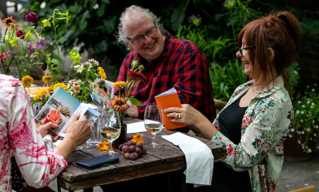 Two people seated outdoors sharing photographs and conversation at a celebration of life meal