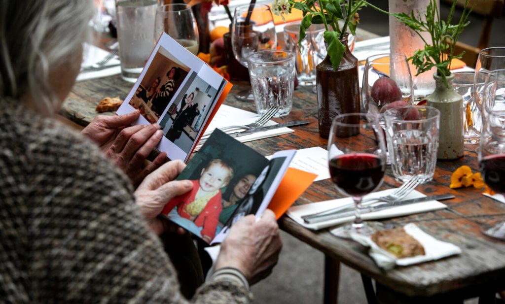 Guests seated at a table looking through photographs during a memorial luncheon
