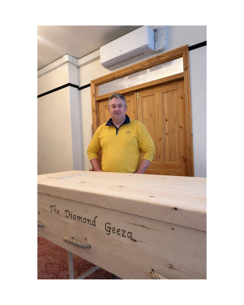 Craftsman Paul Barnett standing next to hand built custom coffin