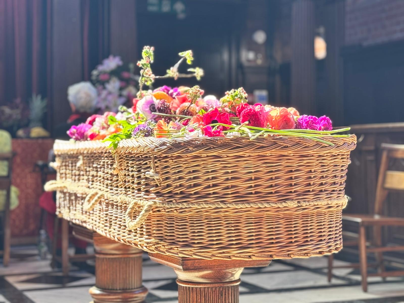 Woven Farewells sustainable English Willow double ended coffin bath in sunlight with with wild flowers