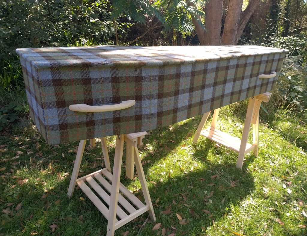 Harris Tweed coffin, on trestle legs bathed in sunshine in a natural woodland burial environment