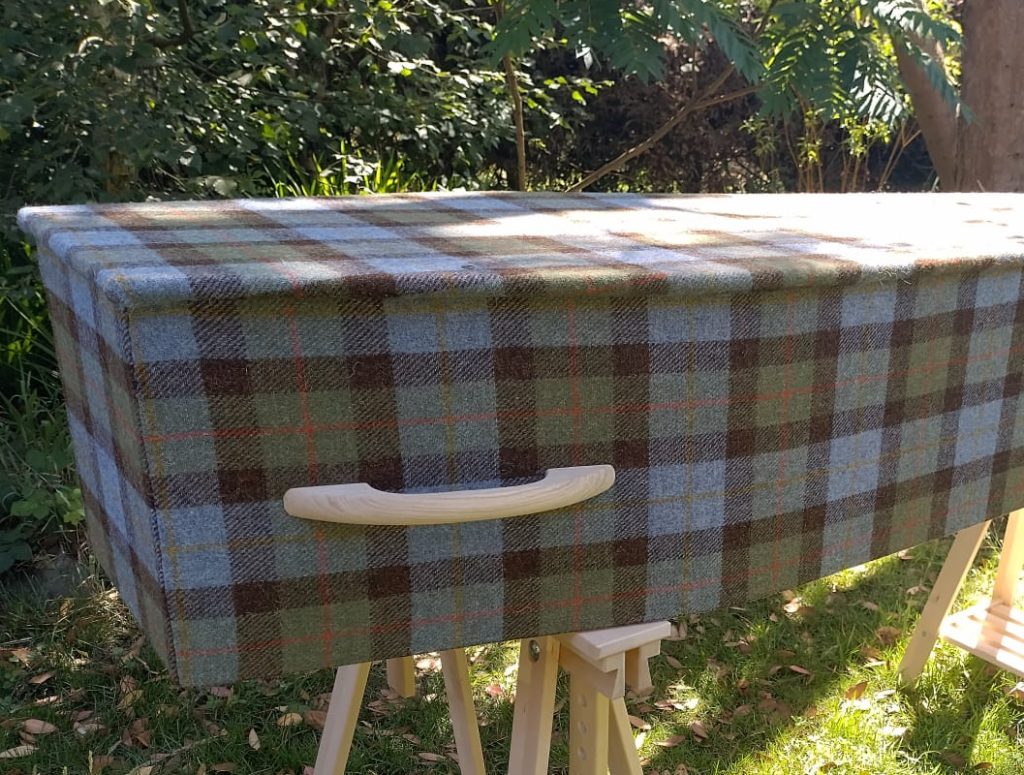 Harris Tweed coffin, on trestle legs bathed in sunshine in a natural woodland burial environment