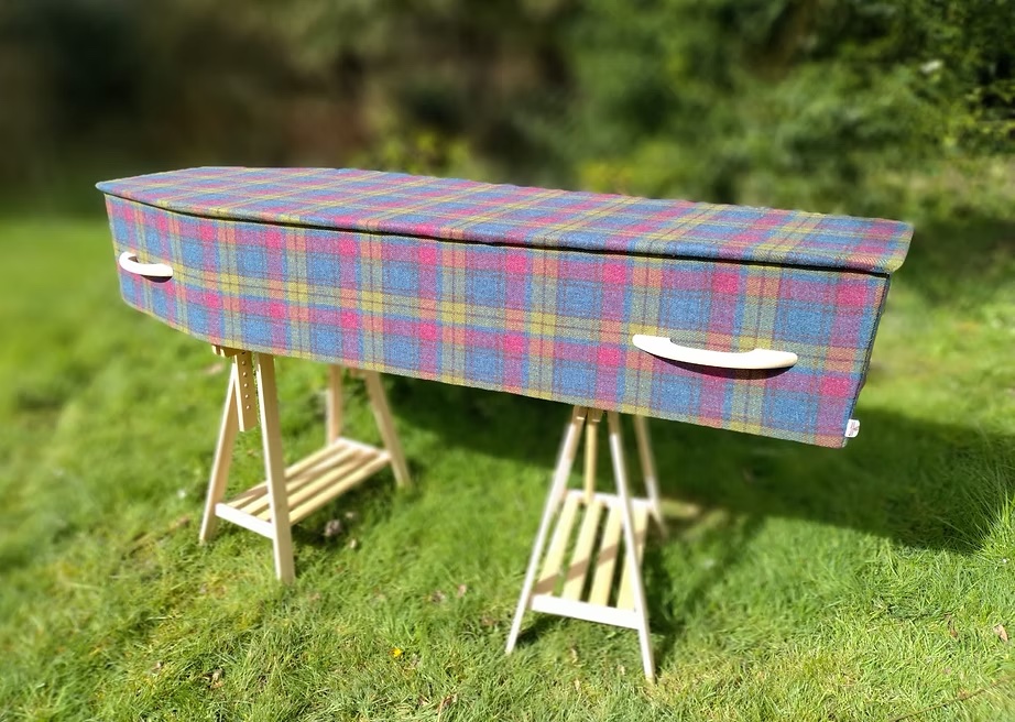 Pink Harris Tweed Sustainable Coffin on trestles in the natural woodland made by The Woollen Cwtch Company